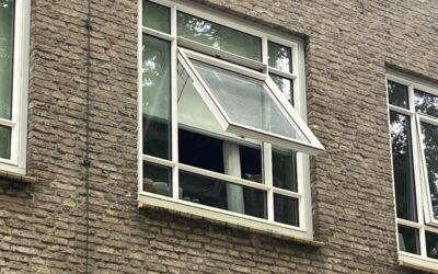 Lägenhetsbyggnad i rött tegel med ett öppet fönster för att visa hur bra det är med fönsterbyten i Stockholm
